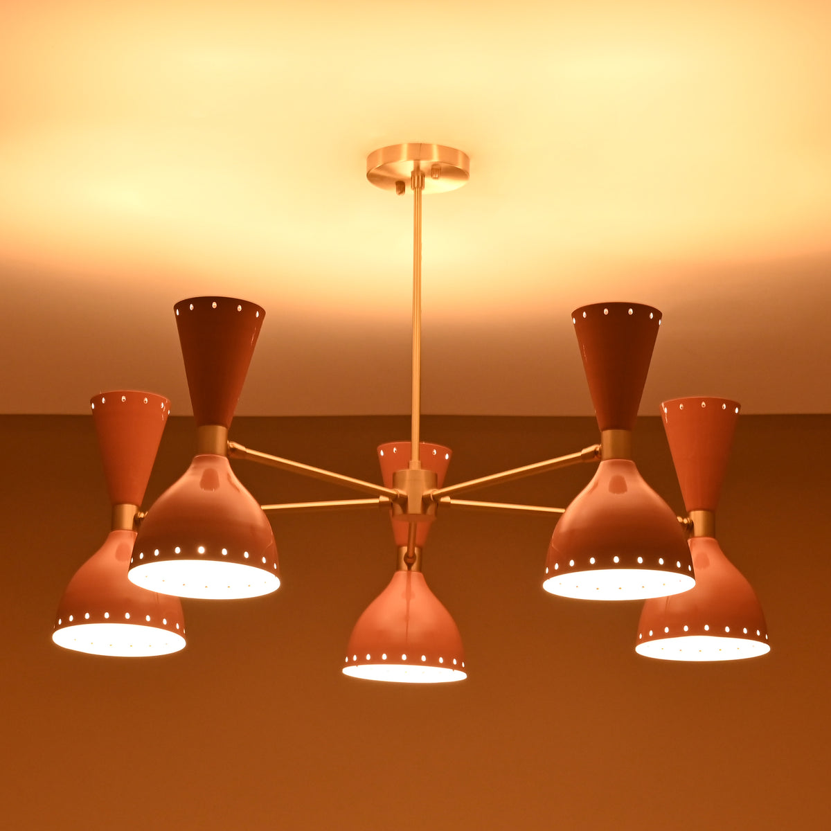 Mid-century modern peach and brass chandelier glowing warmly in ambient lighting