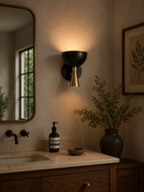 Milan black and brass dome wall sconce installed above bathroom vanity with warm ambient lighting – Model 32797