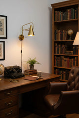 Milan cone shade wall sconce with raw brass finish, round backplate, and long adjustable arm