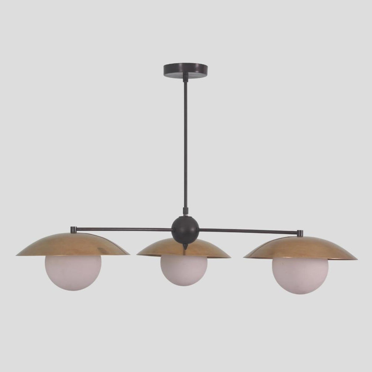 Minimalist 3-light chandelier with round globe shades and brushed brass bowl covers, designed for modern living areas and boutique spaces.