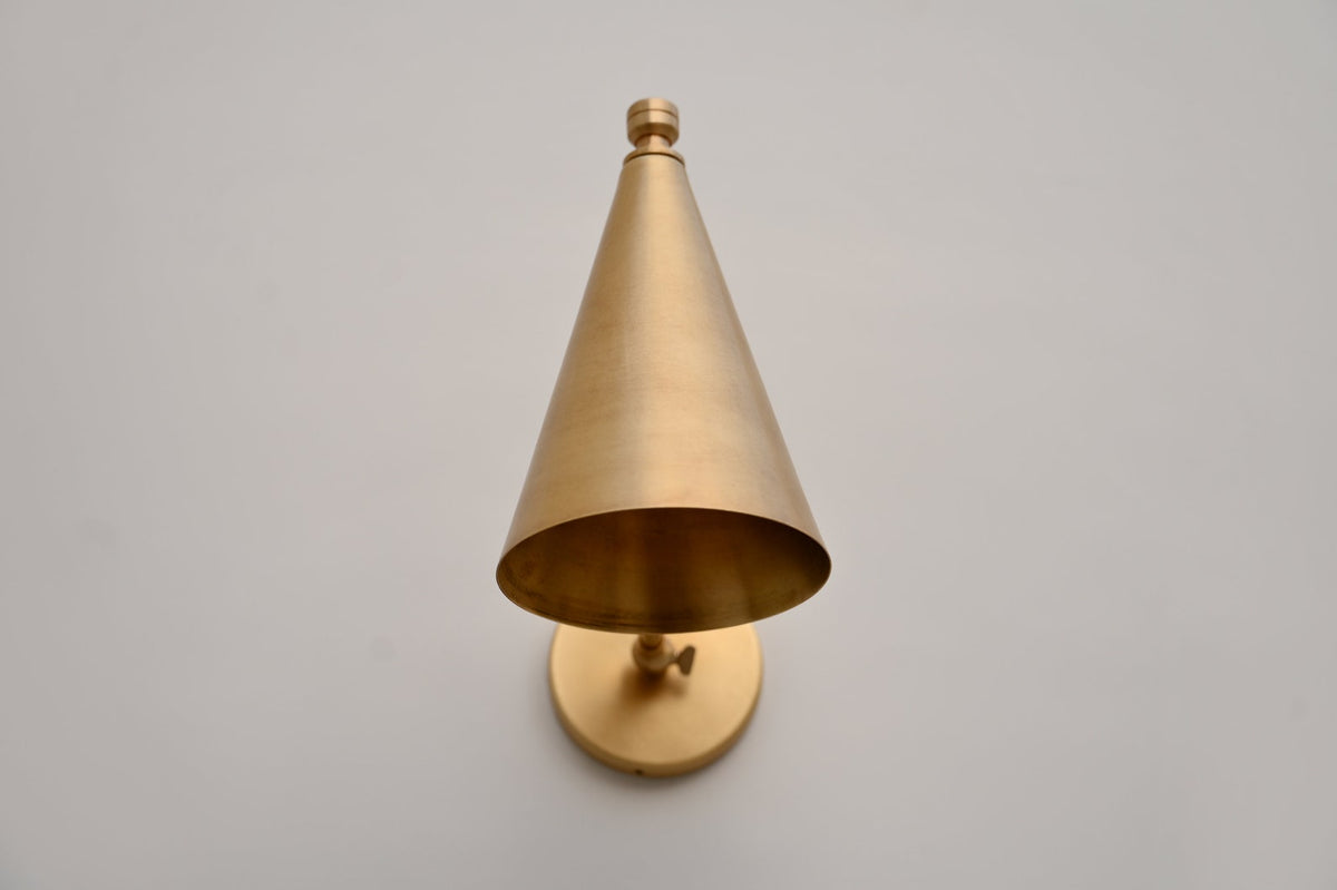 Front view of minimalist brass cone wall light with precision-crafted conical shade and solid brass build.