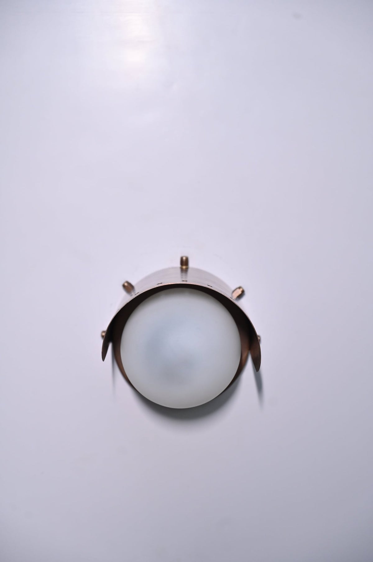 Front view of minimalist brass globe wall light with curved brass shade in satin finish