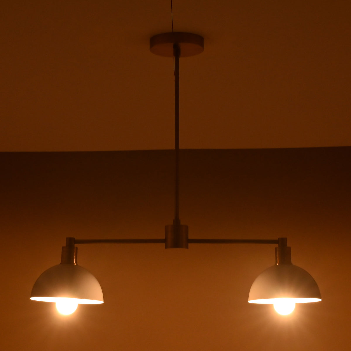 Modern brass pendant light with soft symmetrical glow from two domes