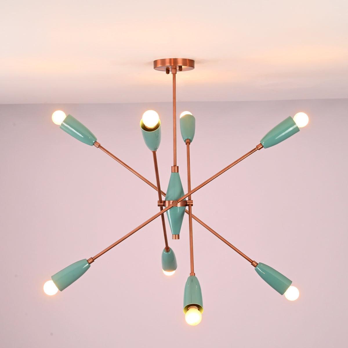 Bottom view of mint green brass chandelier highlighting radial arm layout and warm light distribution.