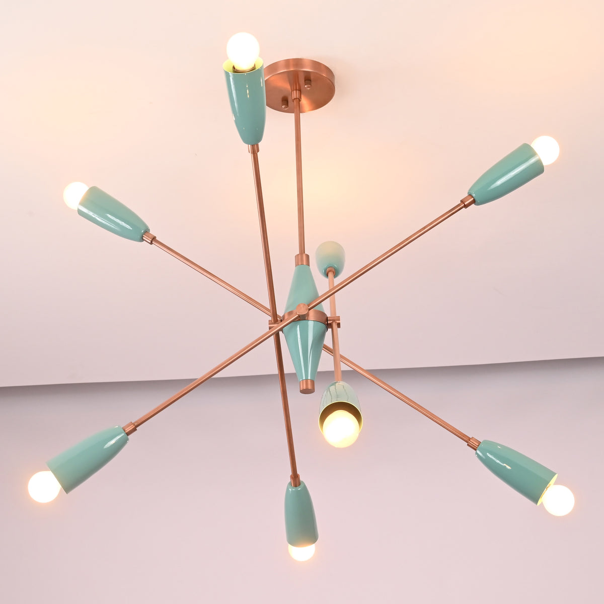 Angled view of mint green brass sputnik chandelier with eight lights creating warm ambient illumination.