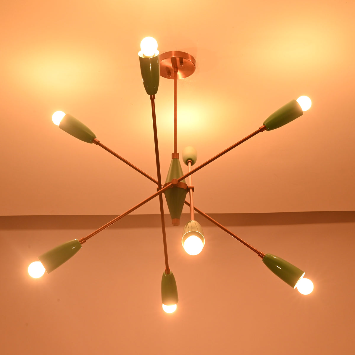 Mint green sputnik chandelier casting warm ambient light across the ceiling in a dark setting.