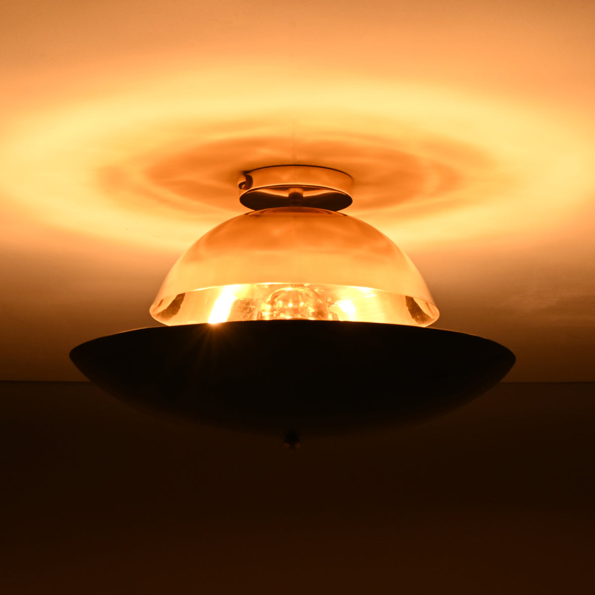 Warm halo lighting effect around mixed-finish brass flushmount featuring polished brass dome and illuminated interior bulb.