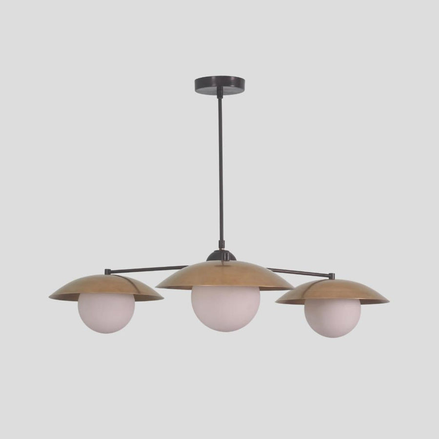 Modern brass chandelier with three globe lights and bowl-shaped shades, minimalist pendant design for dining and living spaces.
