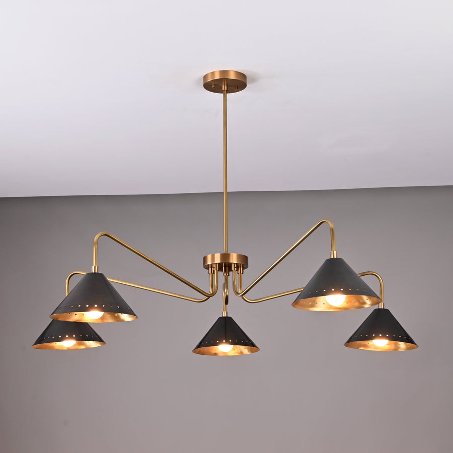 Front view of handcrafted 5-light brass chandelier featuring matte-black perforated cone shades and brushed brass arms.