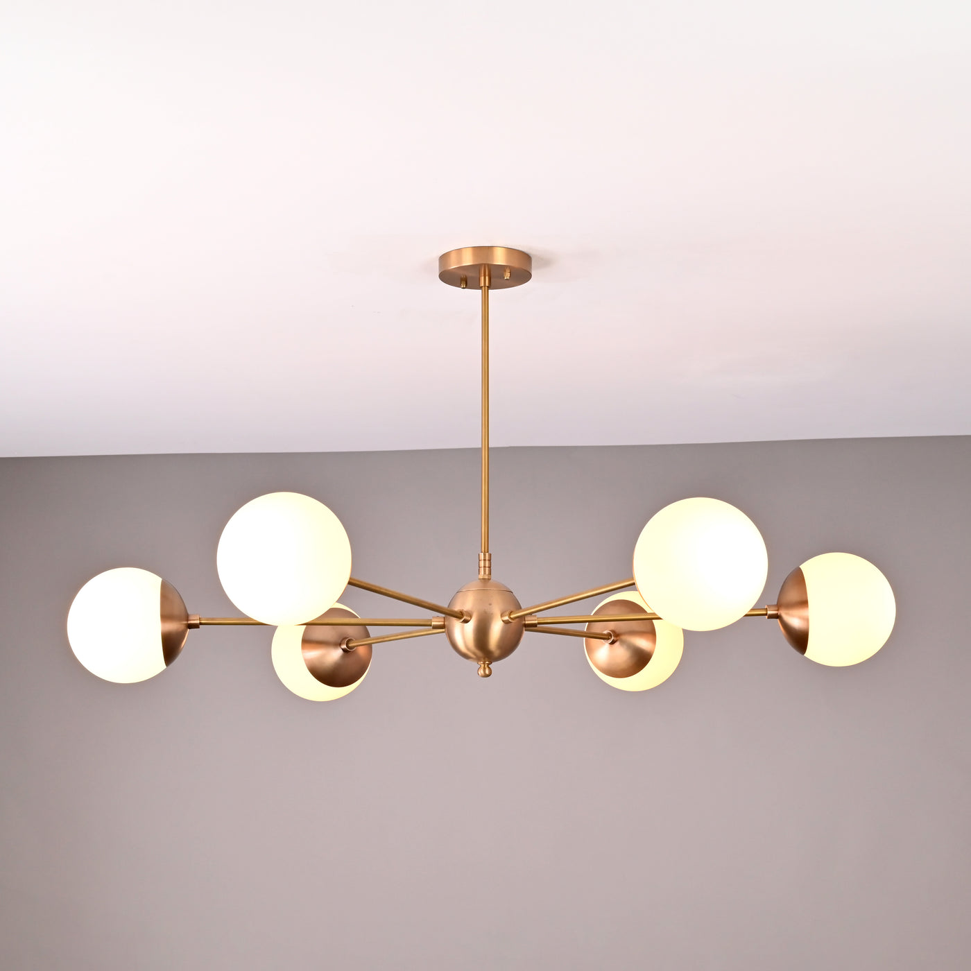 Handmade 6-globe brass chandelier featuring opal glass globes and brushed brass finish for modern interiors.