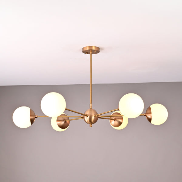 Handmade 6-globe brass chandelier featuring opal glass globes and brushed brass finish for modern interiors.