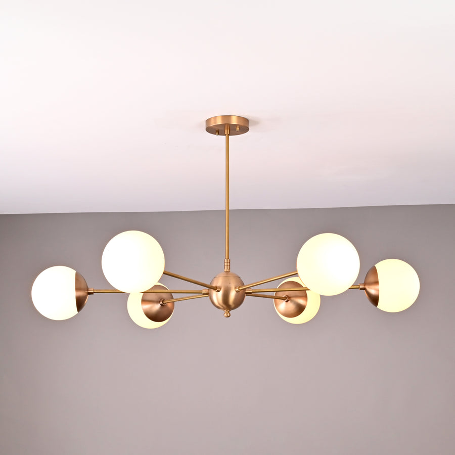 Handmade 6-globe brass chandelier featuring opal glass globes and brushed brass finish for modern interiors.
