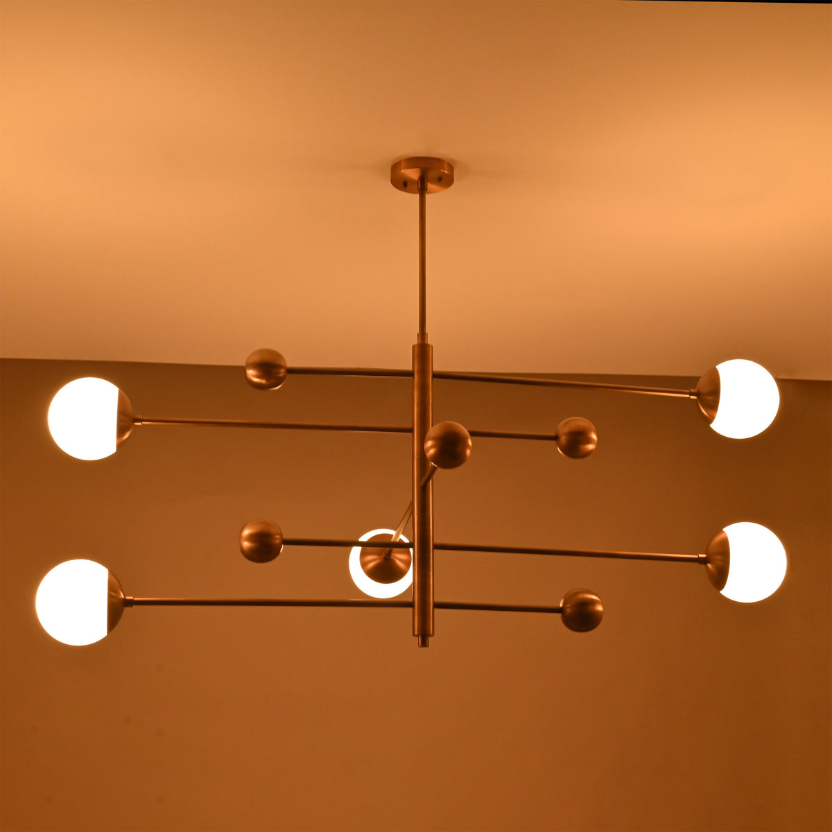 Modern bedroom globe ceiling light with five lights arranged on a clean architectural brass frame
