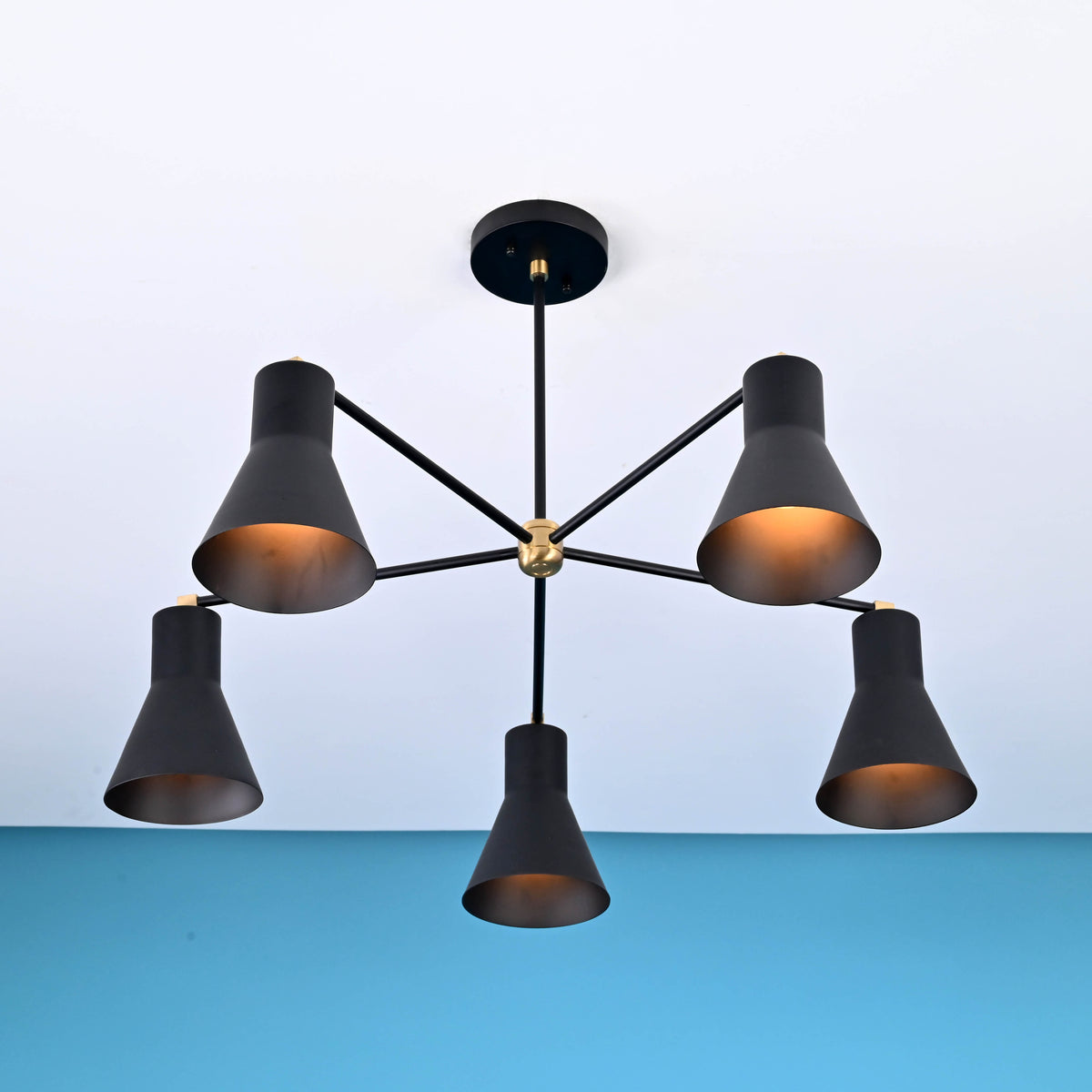 Angled view of 5 cone brass chandelier showing warm glow and tapered cone metal shades