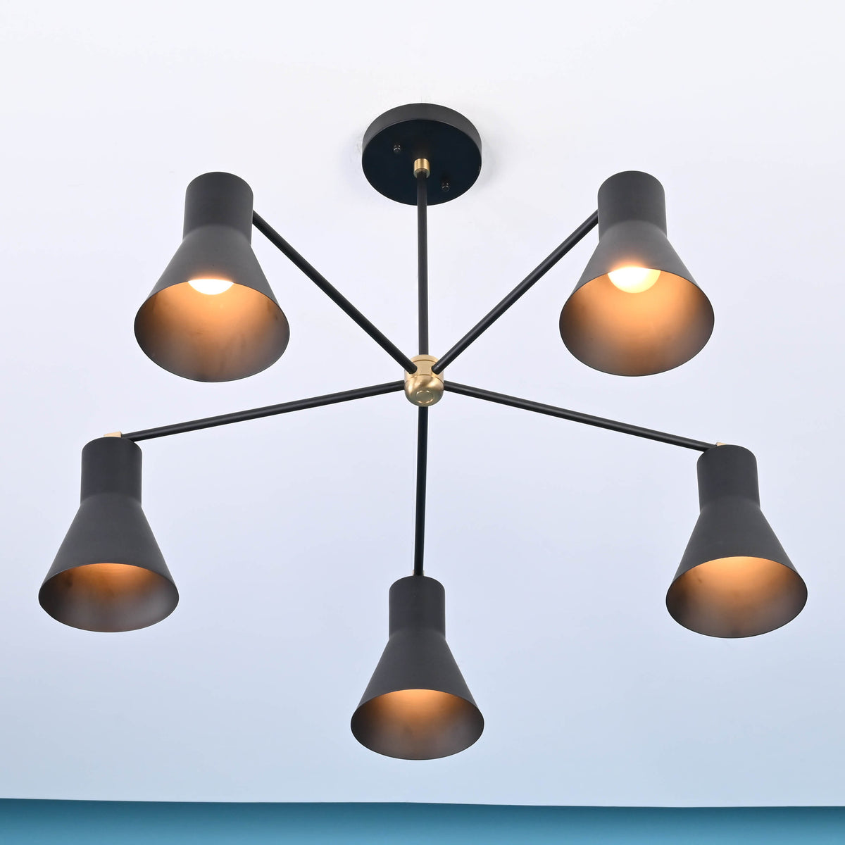 Bottom view of modern brass 5 cone chandelier with warm ambient lighting and symmetrical arm layout