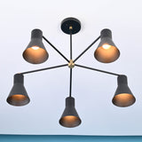 Bottom view of modern brass 5 cone chandelier with warm ambient lighting and symmetrical arm layout