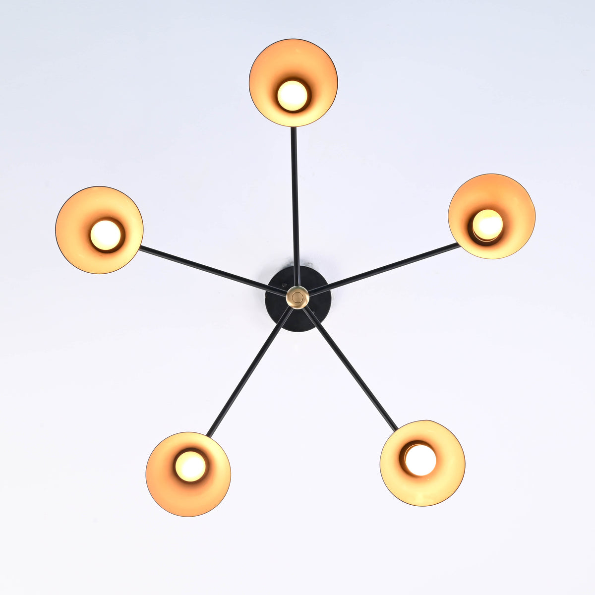 Ceiling view of modern brass 5 cone chandelier with balanced arms and warm indirect lighting