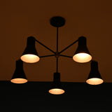 Modern brass 5 cone chandelier illuminated in dark room creating warm ambient lighting effect