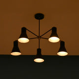 Soft ambient lighting from modern brass 5 cone chandelier in low light interior setting