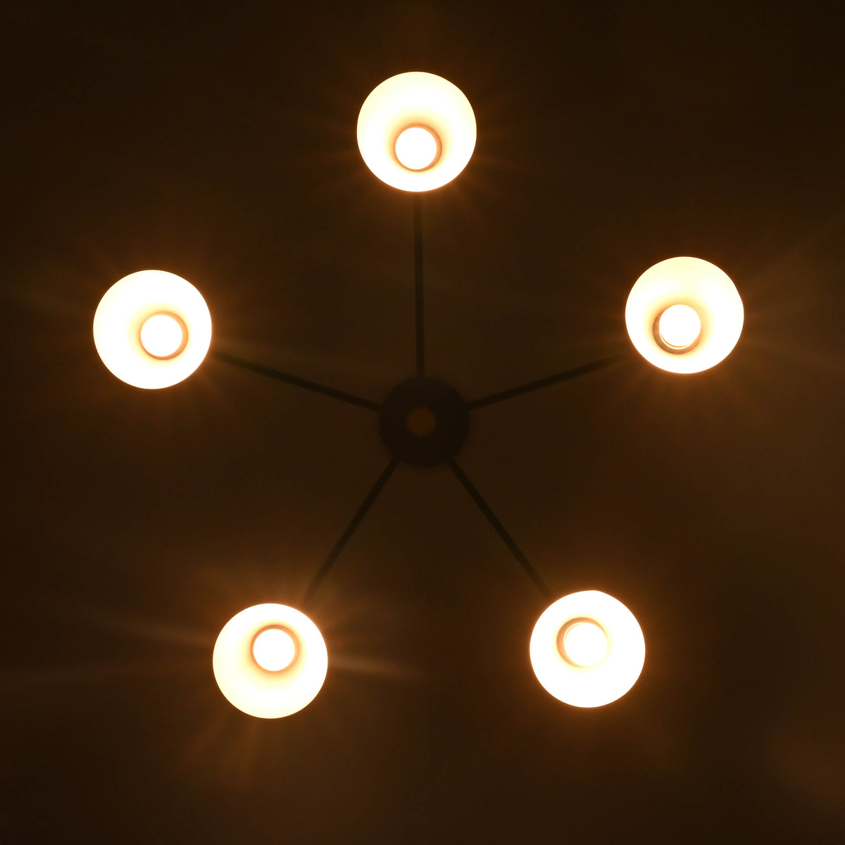 Symmetrical bottom view of 5 cone brass chandelier highlighting modern industrial geometry