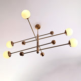 Side-angle view of a modern 5-light brass chandelier with round opal glass globes and minimalist brass arms.