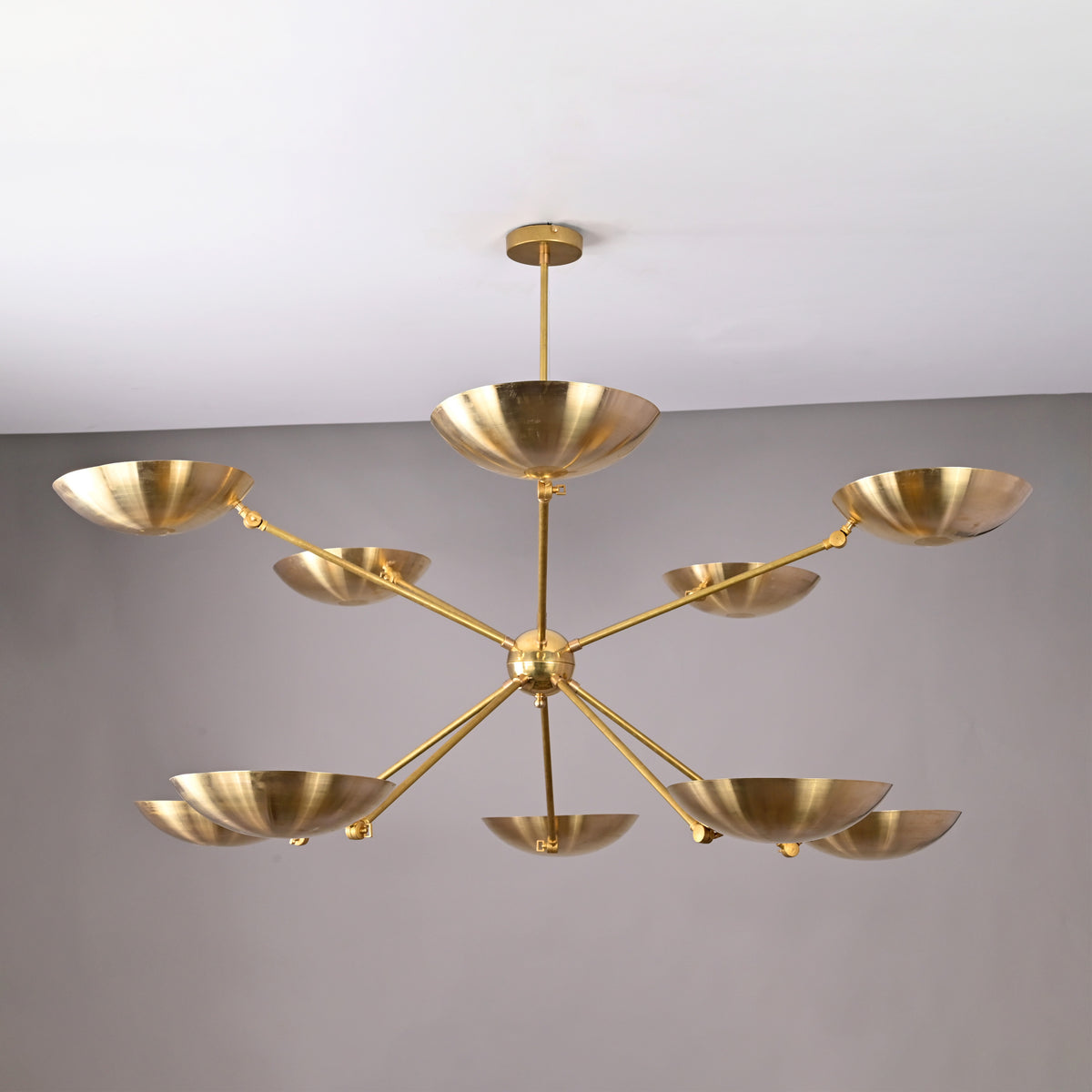Modern handmade brass chandelier featuring ten polished bowl shades arranged in a radial formation.