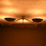 Modern brass ceiling light producing indirect upward glow through sculpted bowl-shaped shades.