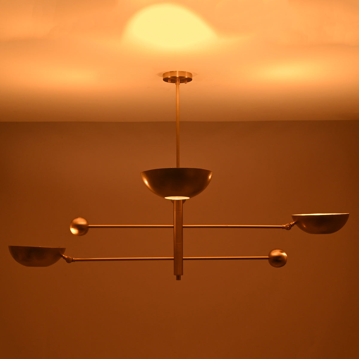 Modern brass ceiling chandelier casting soft indirect glow across the ceiling