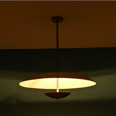 Modern brass ceiling light emitting a warm ambient glow, designed with a sleek dome silhouette, perfect for cozy dining or living areas.