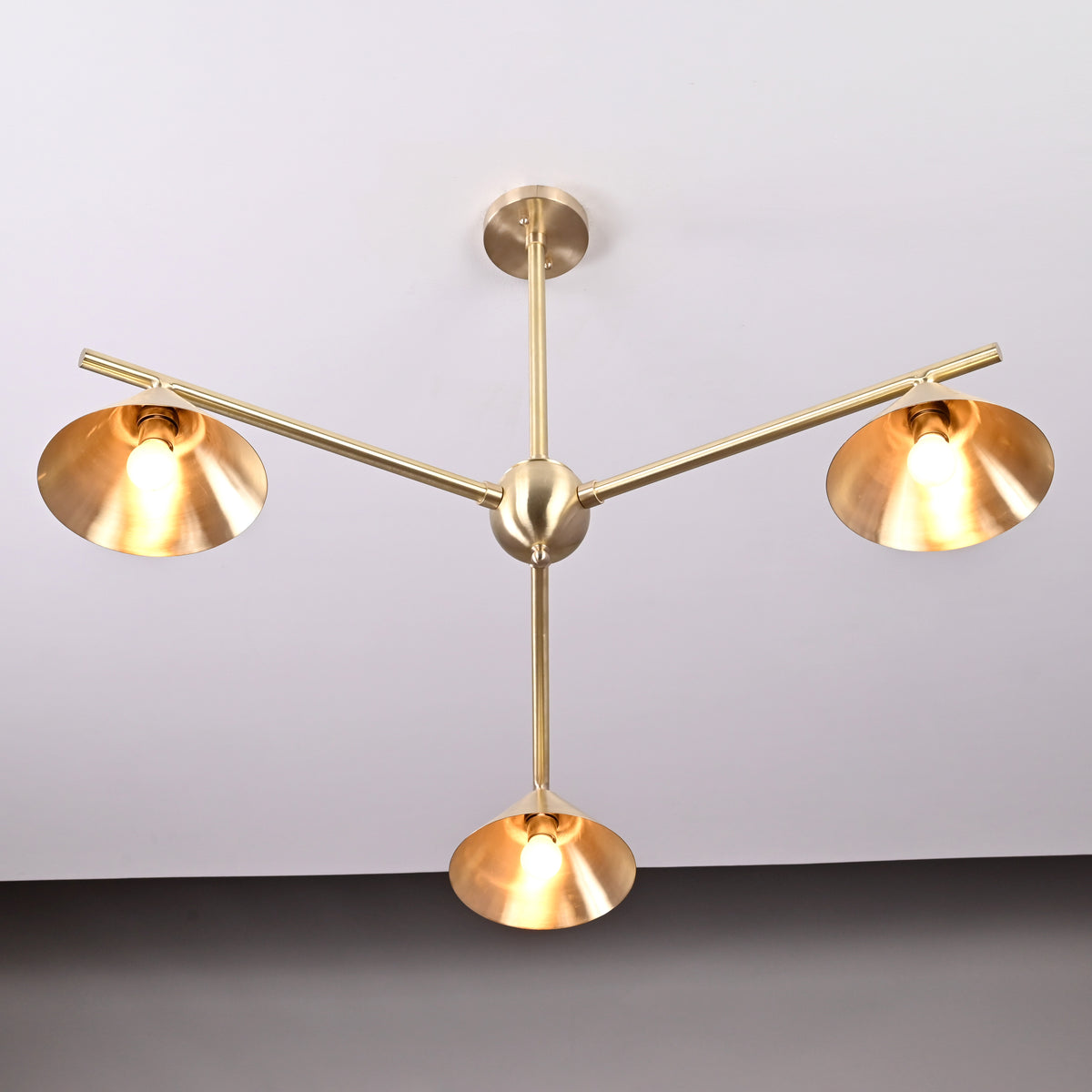 Handmade modern brass ceiling chandelier with three angled cone shades and sleek geometric arms.