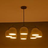 Minimalist 8-light chandelier in brass with soft evening light illuminating ivory dome shades.