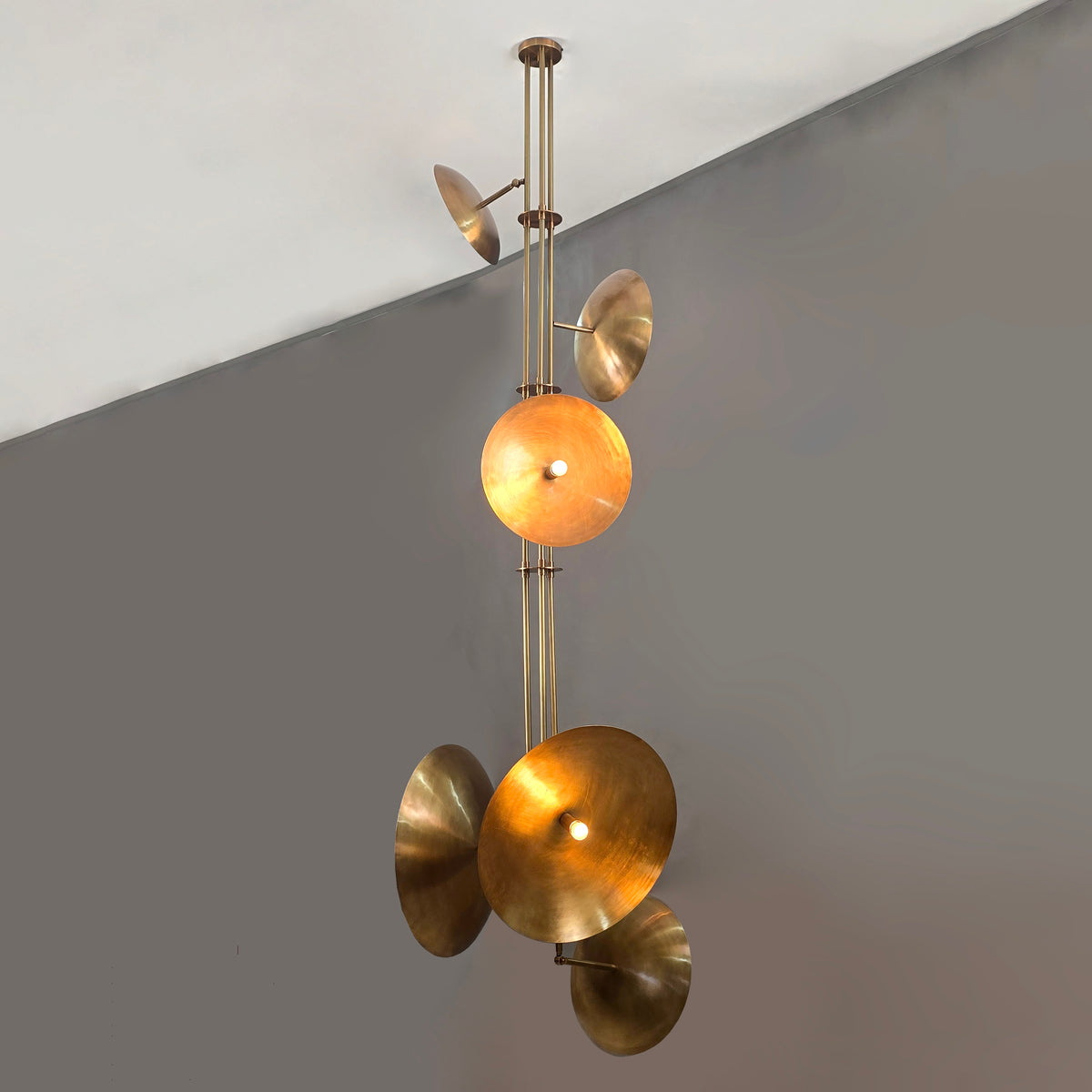 Brass disc chandelier glowing in modern space, warm ambient lighting