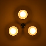 Brass disc flush mount ceiling light glowing warmly in a dark interior, highlighting opal glass globes.