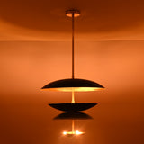Modern brass disc chandelier casting upward indirect light, creating a warm ceiling wash effect