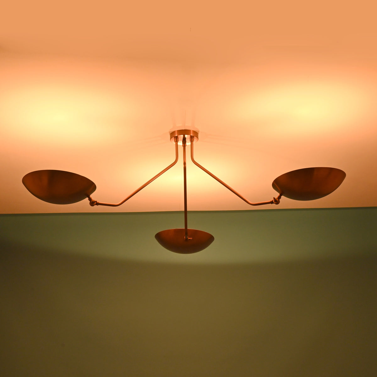 Modern brass flush mount ceiling light with bowl shades creating symmetrical ambient illumination across the ceiling