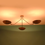 Modern brass flush mount ceiling light with bowl shades creating symmetrical ambient illumination across the ceiling