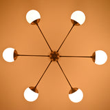 Warm-lit brass chandelier with six glowing globe shades creating a soft ambient atmosphere.