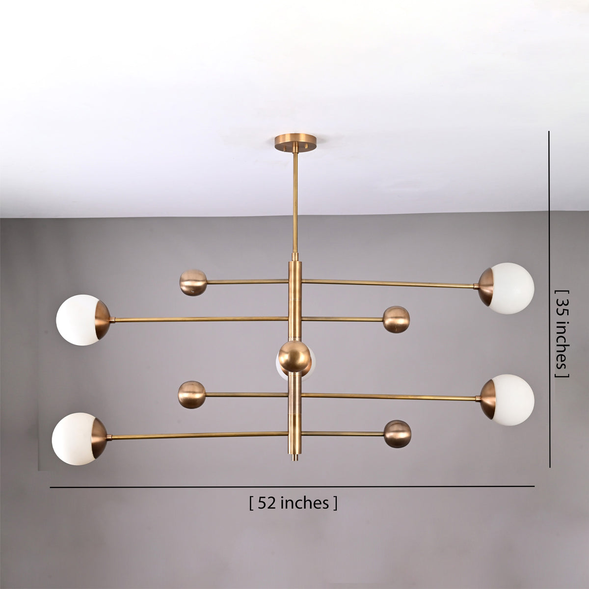 Modern brass globe chandelier shown from below with five opal glass shades and balanced linear arms