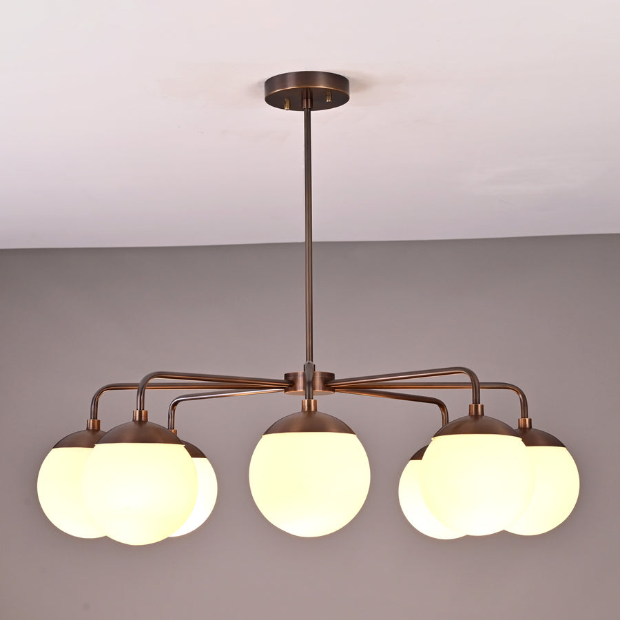 Front view of modern 8-light brass chandelier with opal glass globes and minimalist curved arms.