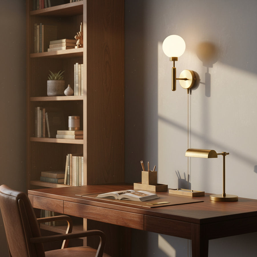 Modern brass globe wall light with round canopy, vertical stem, pull chain control, and soft warm ambient illumination