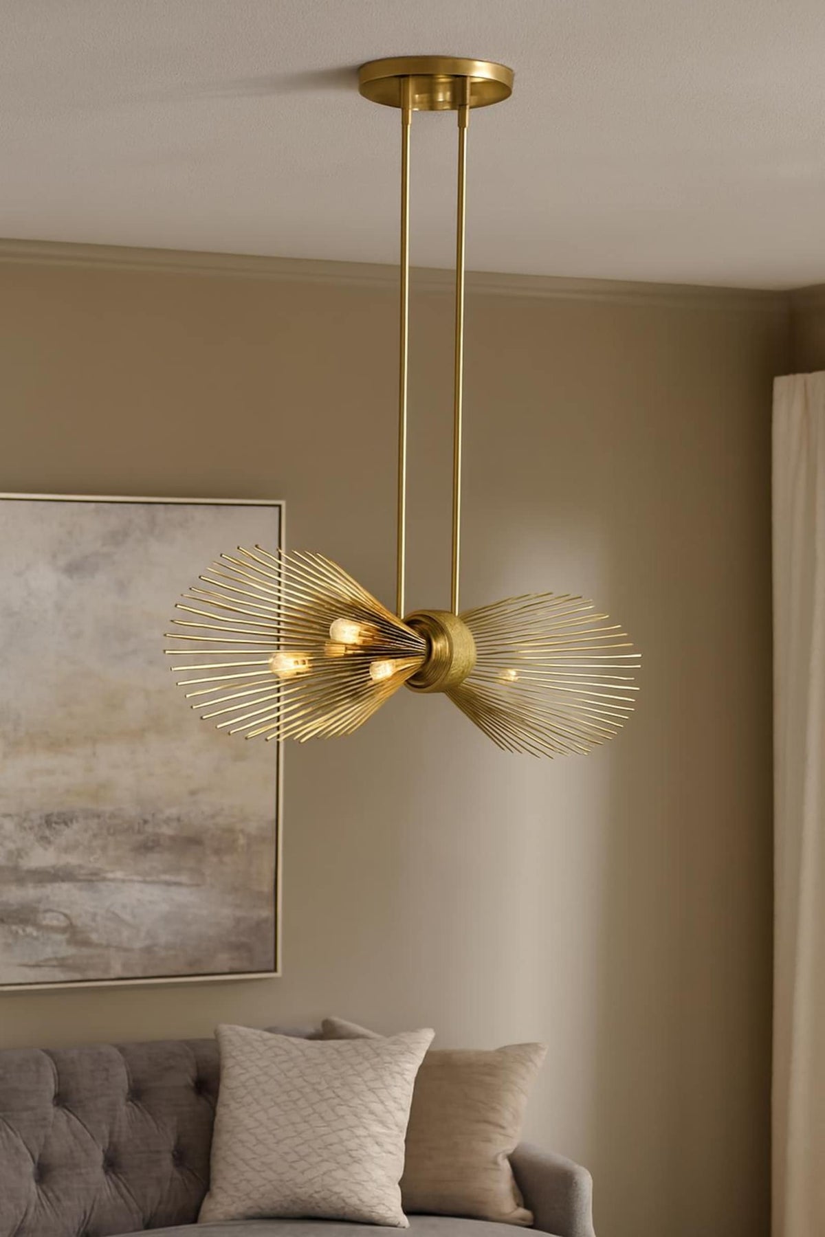 Modern brushed brass linear chandelier installed in living room, sculptural industrial lighting with warm ambient glow