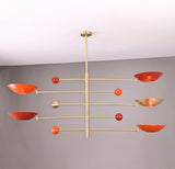 Modern brass mobile chandelier with red bowl-shaped shades featuring sculptural balanced arms handcrafted by Brass Leaf Studio.