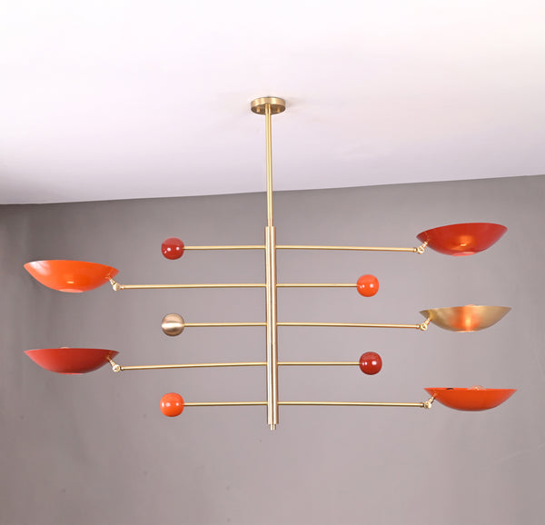 Modern brass mobile chandelier with red bowl-shaped shades featuring sculptural balanced arms handcrafted by Brass Leaf Studio.