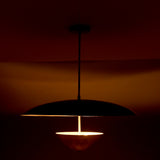 Evening profile view of modern brass pendant with dual shades producing soft, diffused ambient lighting.