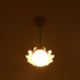 Modern brass pendant light with scalloped shade producing gentle side glow at night.