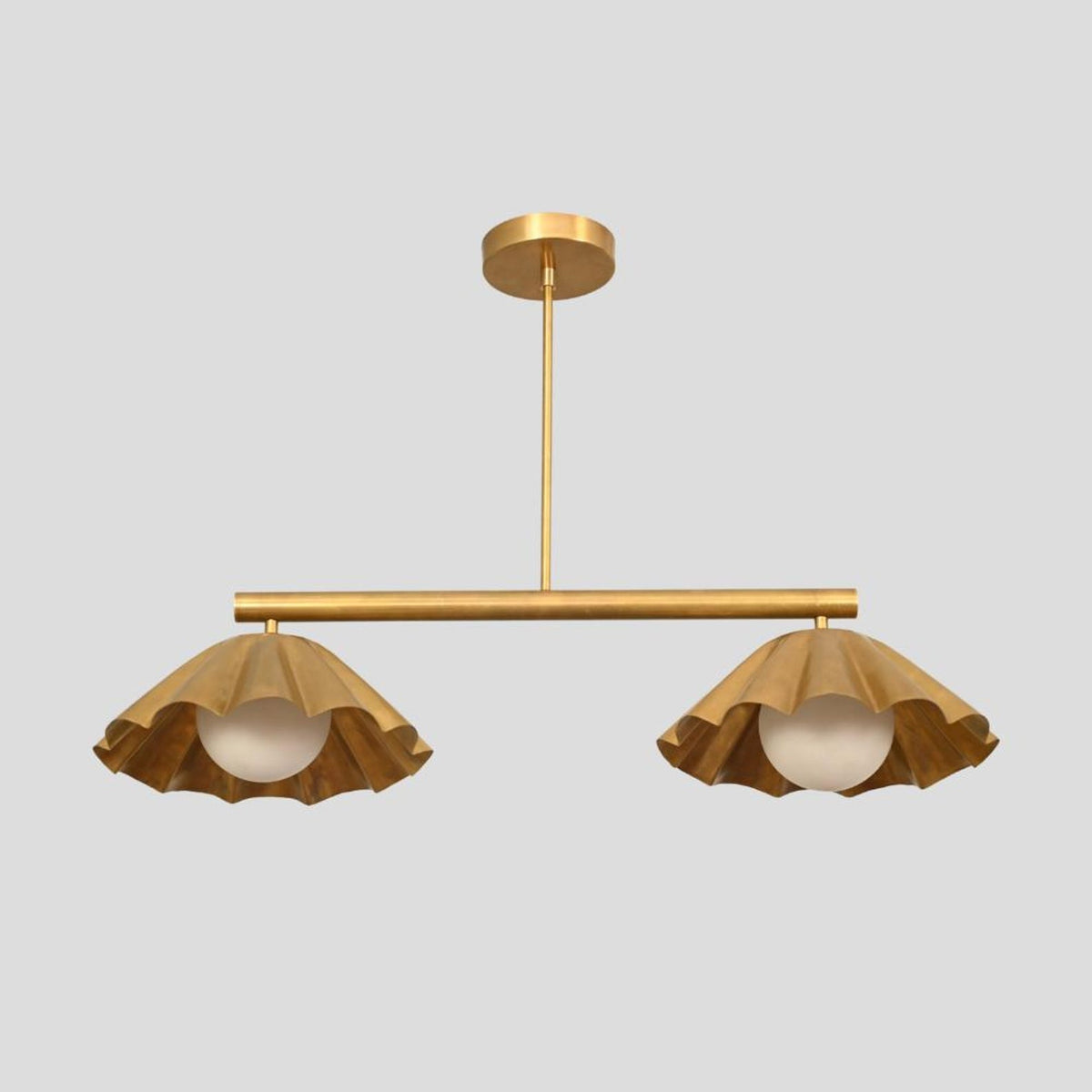 Modern brass pendant chandelier featuring two sculpted ruffle shades with globe bulbs, adding elegance to contemporary spaces.