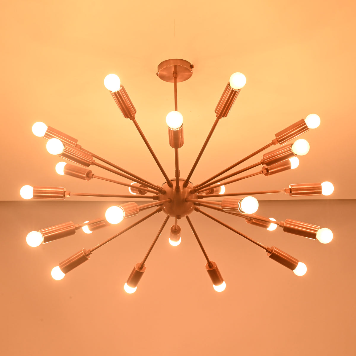 Modern brass sputnik chandelier shown from angled perspective with glowing bulbs in dark space.
