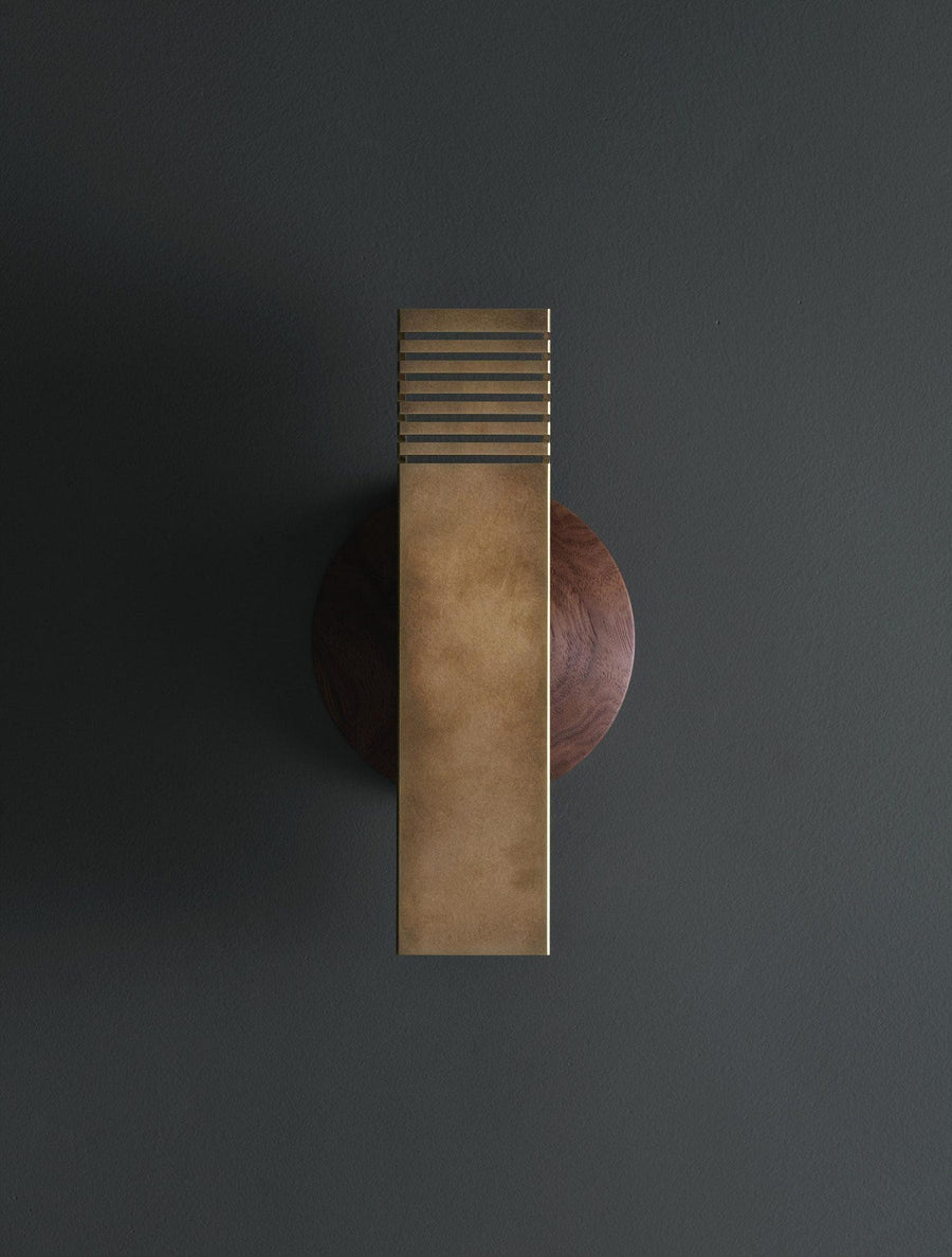 Modern brushed brass wall sconce with rectangular body and slotted top design mounted on dark wall
