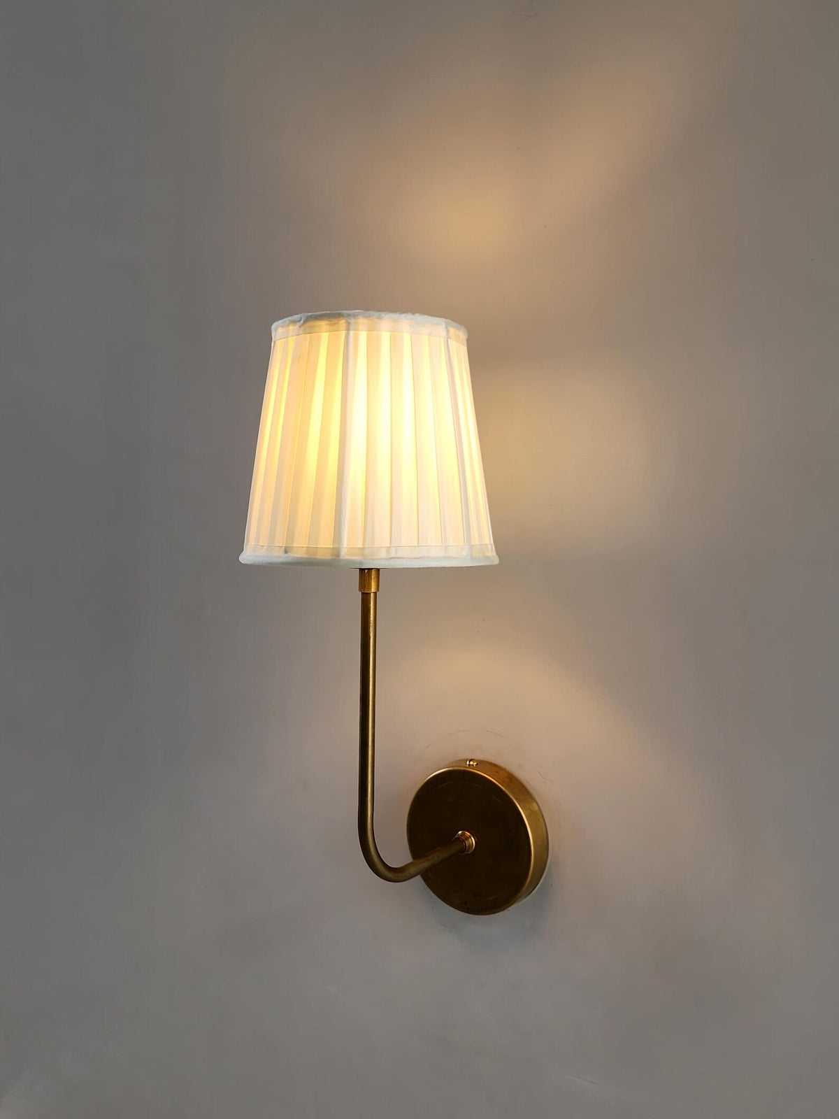 Modern brass wall sconce with pleated lampshade, handcrafted by Brass Leaf Studio.