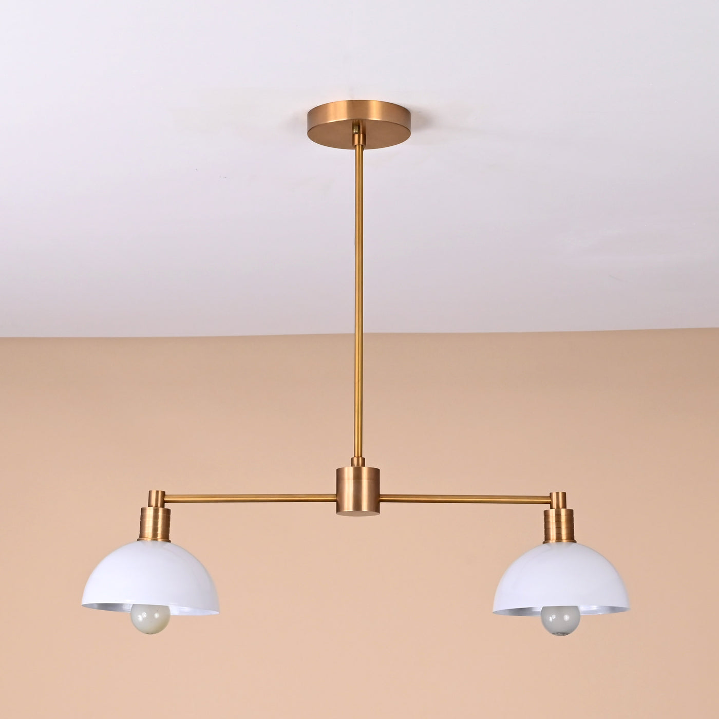 Modern two-light brass pendant with white domed shades and sleek minimalist design